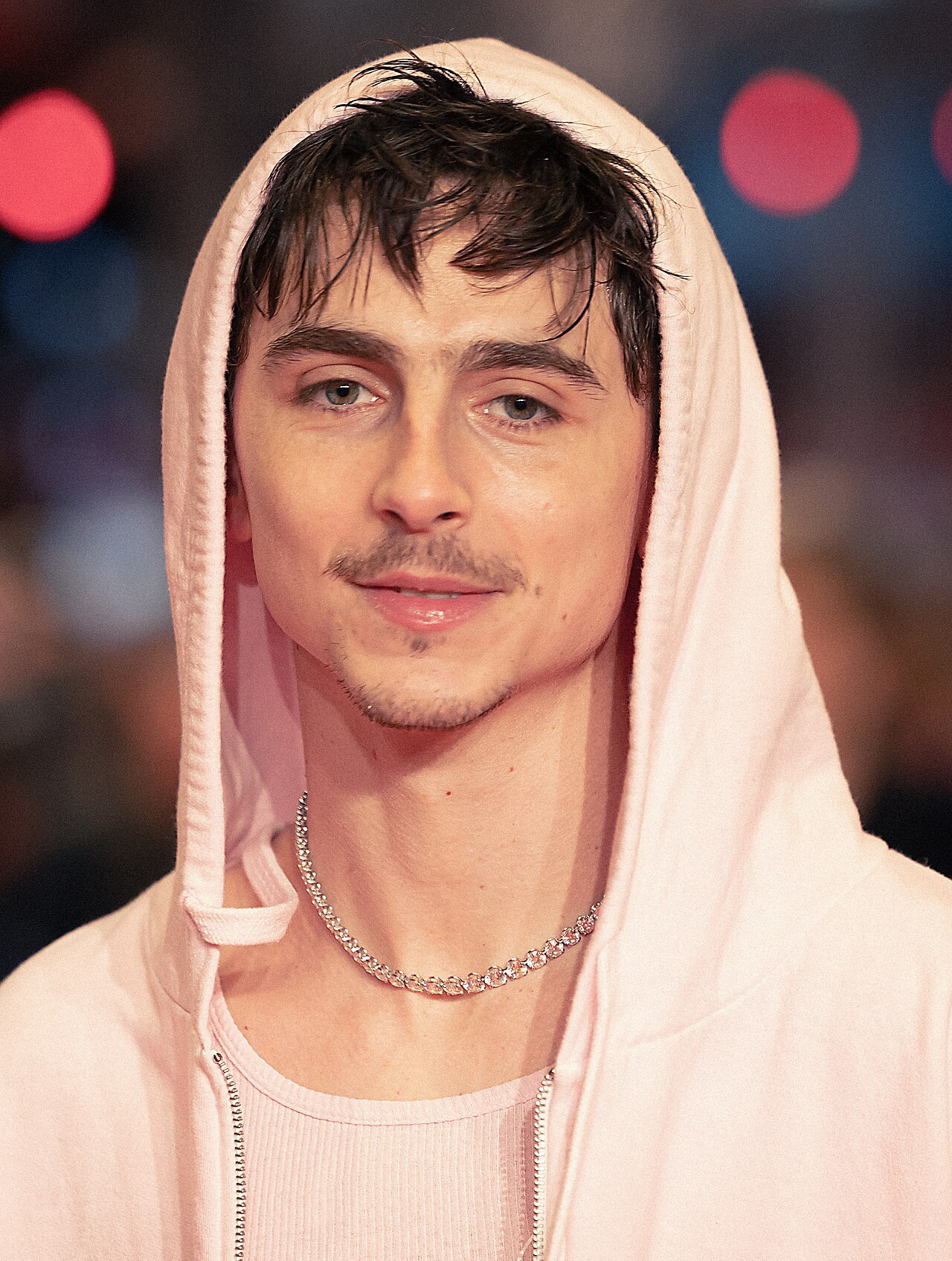 Timothée Chalamet mặc hoodie hồng nhạt với dây chuyền bạc bản to.